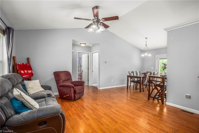 living area with visible vents, light wood-style flooring, baseboards, lofted ceiling, and ceiling fan with notable chandelier
