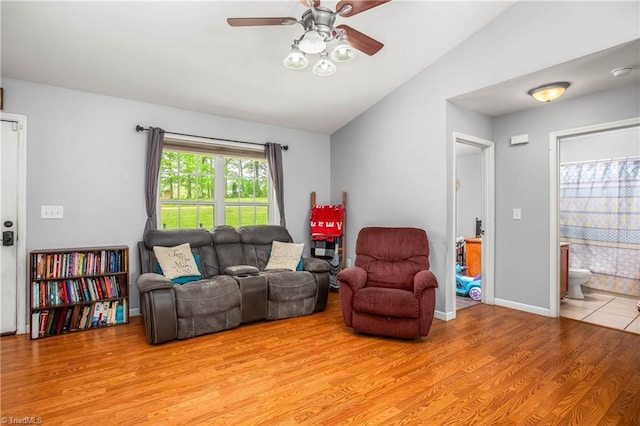 living area with baseboards, light wood-style flooring, ceiling fan, and lofted ceiling