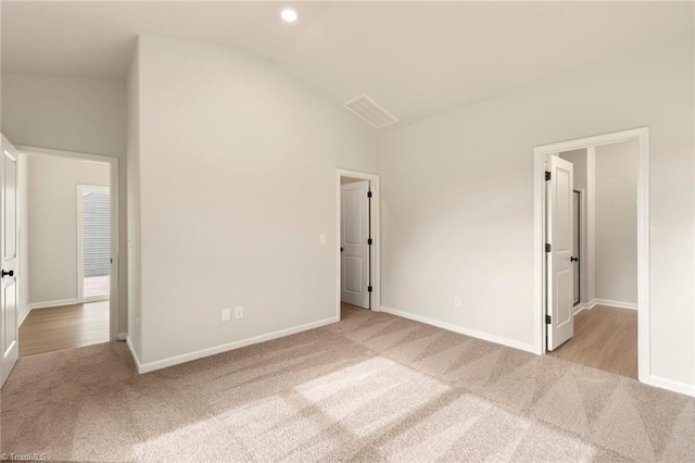 unfurnished bedroom featuring light carpet and vaulted ceiling