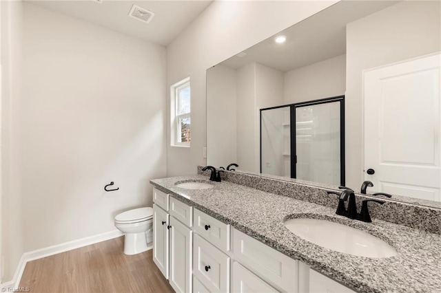 bathroom with hardwood / wood-style floors, vanity, toilet, and walk in shower