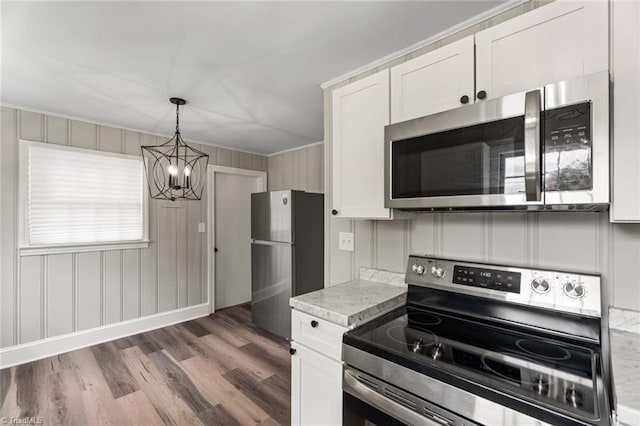 506 W 26th St, Winston-Salem, NC 27105 - kitchen with stainless steel appliances, a chandelier, wood finished floors, white cabinets, and ornamental molding