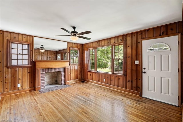 506 W 26th St, Winston-Salem, NC 27105 - unfurnished living room with wood finished floors, a ceiling fan, wood walls, and a brick fireplace