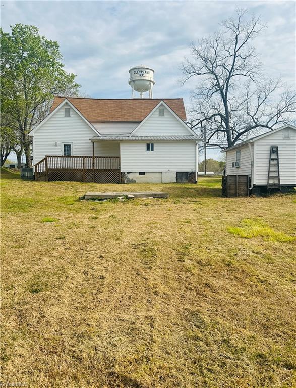 back of property featuring a wooden deck and a lawn