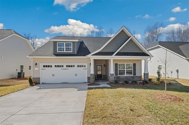 craftsman-style home featuring brick siding, an attached garage, a front lawn, central air condition unit, and driveway