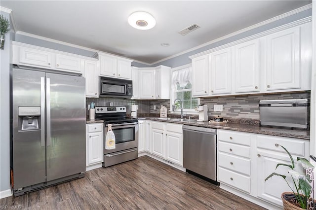 1029 Robbins St, Asheboro, NC 27203 - kitchen with stainless steel appliances, white cabinets, crown molding, dark wood-style floors, and backsplash