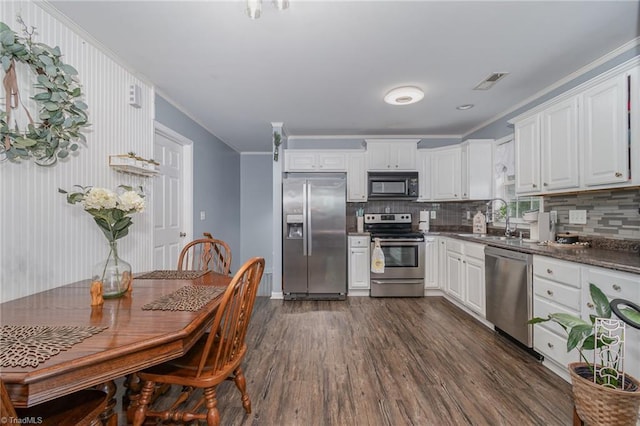 1029 Robbins St, Asheboro, NC 27203 - kitchen with appliances with stainless steel finishes, dark wood finished floors, tasteful backsplash, ornamental molding, and dark countertops
