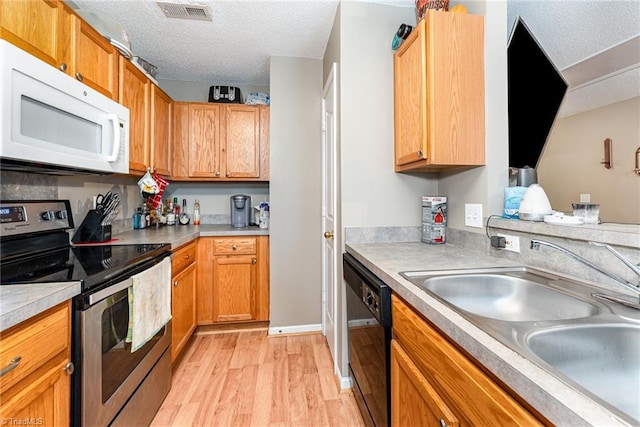 3840 Tarrant Trace Cir, High Point, NC 27265 - kitchen with stainless steel electric range, white microwave, a sink, black dishwasher, and light wood-style floors