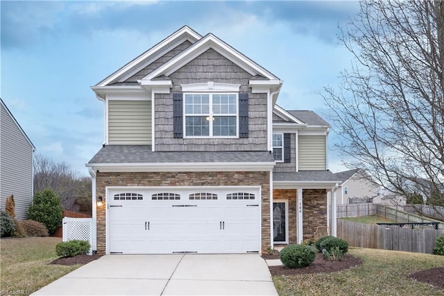 craftsman-style home with stone siding, an attached garage, fence, and driveway