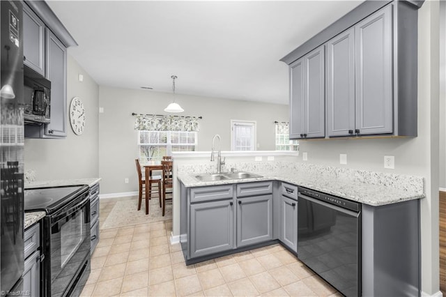 kitchen with a peninsula, a sink, gray cabinets, black appliances, and pendant lighting