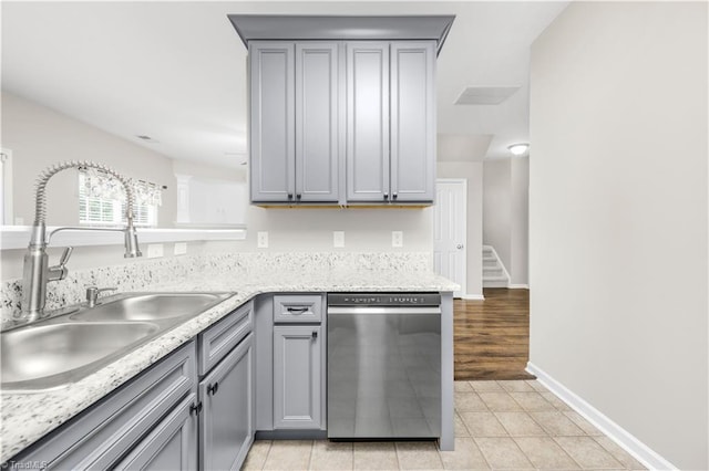 kitchen featuring a sink, light tile patterned floors, dishwasher, and gray cabinetry