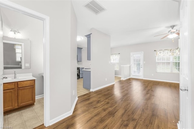 interior space featuring visible vents, ceiling fan, vanity, and wood finished floors