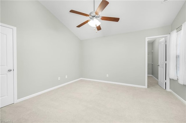 unfurnished bedroom featuring a walk in closet, light carpet, and lofted ceiling