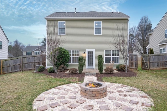 rear view of property with a yard, a fenced backyard, a fire pit, and a patio