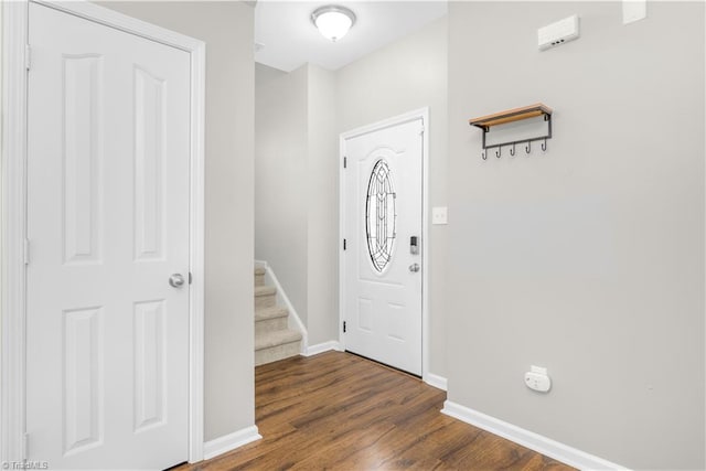 foyer entrance with dark wood-style floors, stairway, and baseboards