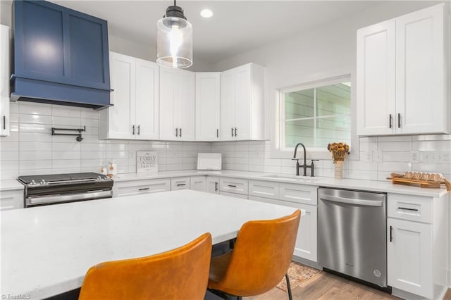 kitchen with a breakfast bar, sink, white cabinets, and appliances with stainless steel finishes