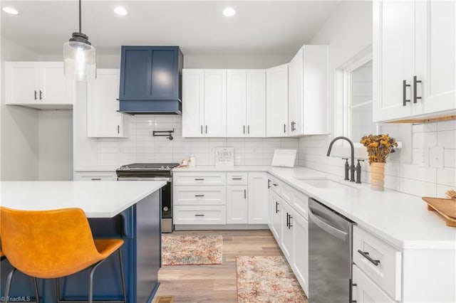 kitchen with white cabinets, hanging light fixtures, sink, appliances with stainless steel finishes, and a kitchen bar