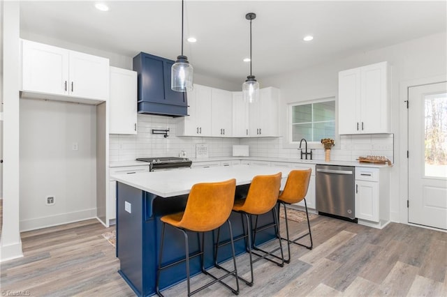 kitchen featuring appliances with stainless steel finishes, light wood-type flooring, white cabinetry, and a kitchen island