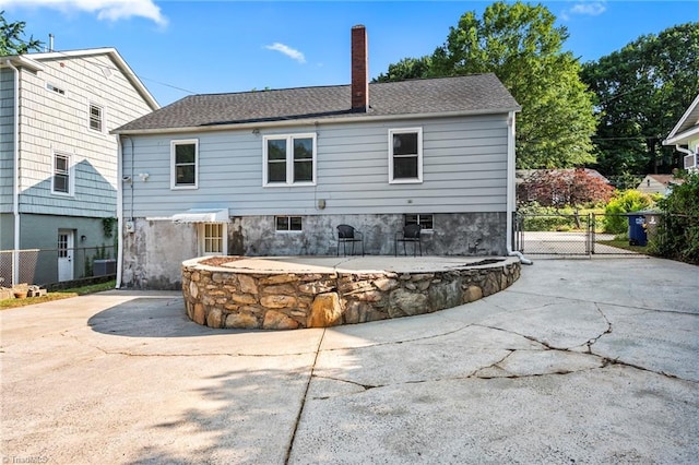 2075 Craig St, Winston-Salem, NC 27103 - back of property featuring a chimney, a shingled roof, concrete driveway, a patio, and a gate