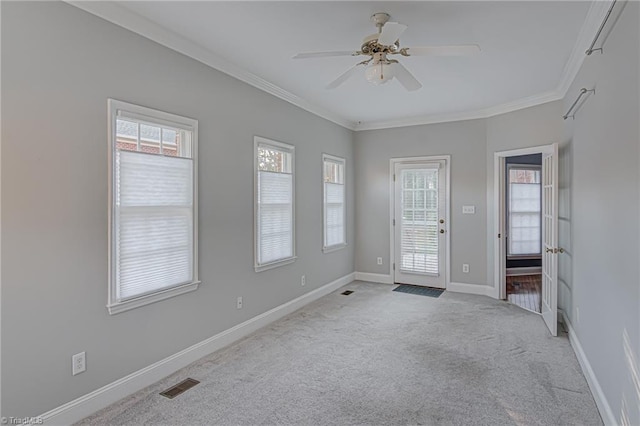 carpeted empty room with a wealth of natural light, ornamental molding, and ceiling fan