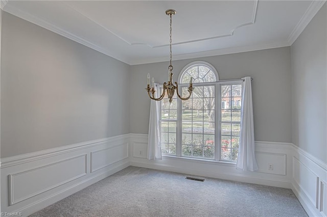 carpeted spare room featuring a chandelier and crown molding