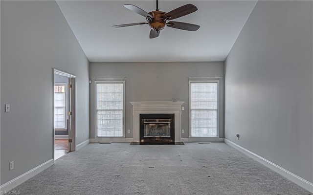 unfurnished living room featuring light carpet, ceiling fan, a healthy amount of sunlight, and lofted ceiling