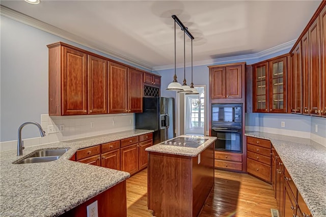 kitchen with sink, crown molding, decorative light fixtures, black appliances, and light wood-type flooring