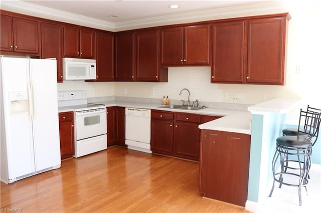 kitchen with light wood-type flooring, ornamental molding, a breakfast bar, white appliances, and sink