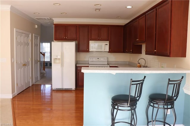 kitchen featuring a kitchen bar, white appliances, ornamental molding, and sink