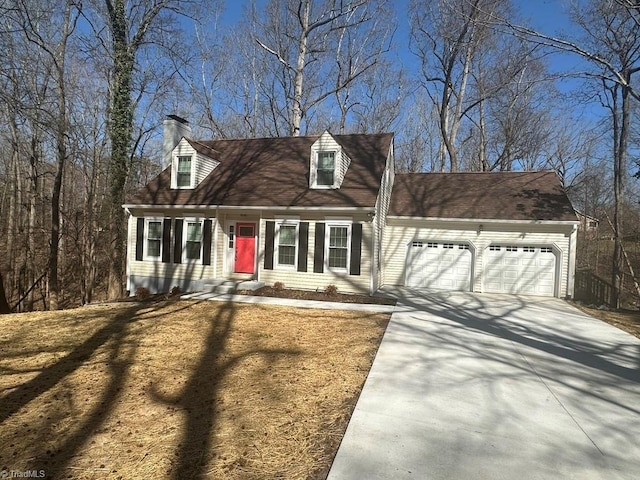 cape cod home with a chimney, concrete driveway, and an attached garage