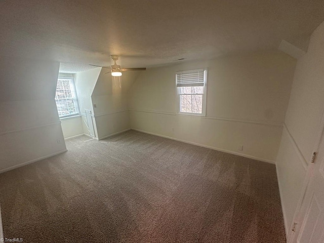 spare room with a healthy amount of sunlight, light colored carpet, baseboards, and a ceiling fan