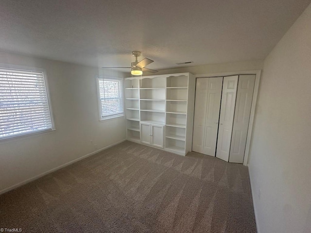 unfurnished bedroom featuring visible vents, carpet, a closet, a textured ceiling, and a ceiling fan