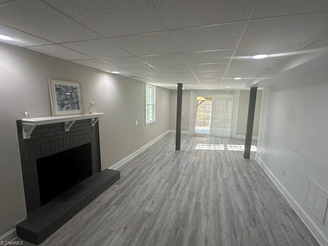 basement with visible vents, a brick fireplace, baseboards, and wood finished floors