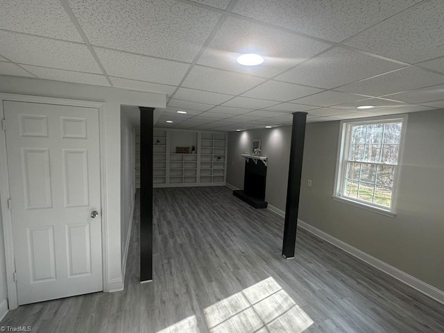 below grade area with wood finished floors, baseboards, and a drop ceiling