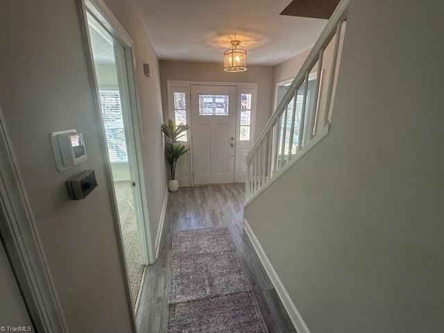 foyer with stairs, wood finished floors, and baseboards