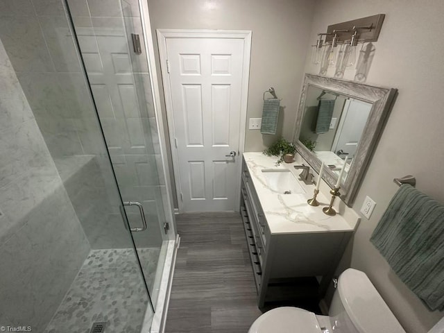 bathroom featuring toilet, a stall shower, and vanity