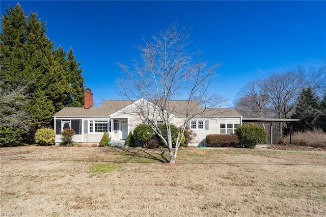 view of front of house featuring a carport, a front yard, and a chimney