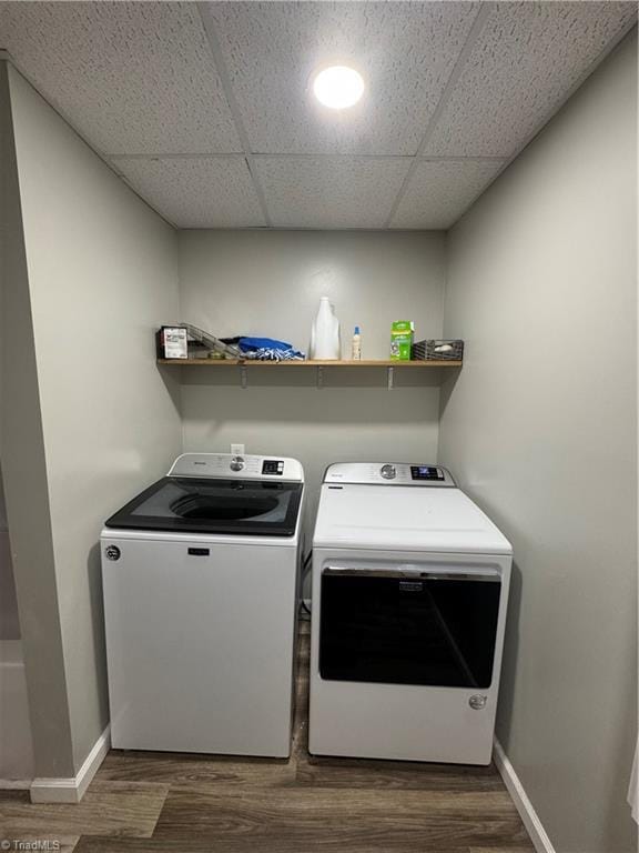 clothes washing area with washer and dryer, baseboards, and dark wood-style floors