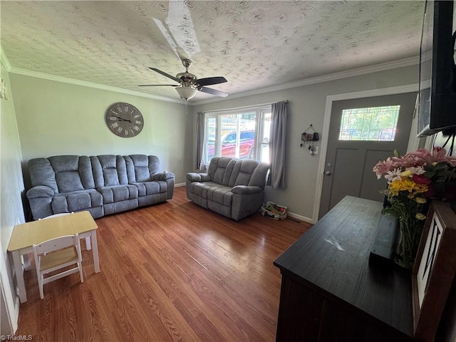 living area with plenty of natural light, wood finished floors, baseboards, and crown molding