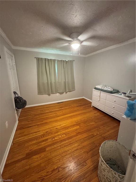 bedroom featuring wood finished floors, baseboards, ornamental molding, a textured ceiling, and a ceiling fan