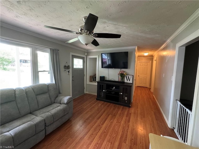 living area with wood finished floors, baseboards, a ceiling fan, crown molding, and a textured ceiling