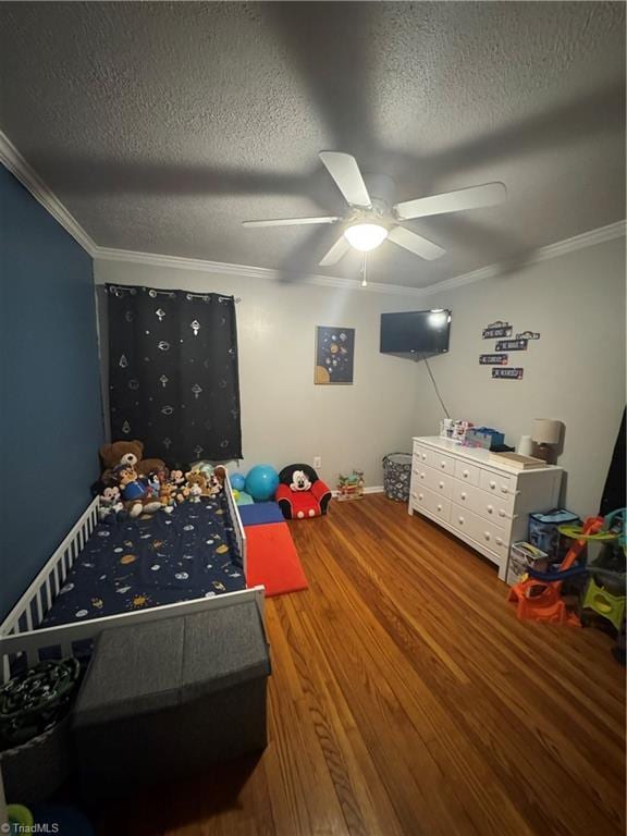 bedroom featuring wood finished floors, a textured ceiling, crown molding, a ceiling fan, and baseboards