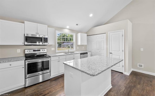 kitchen with a kitchen island, appliances with stainless steel finishes, sink, white cabinets, and light stone countertops