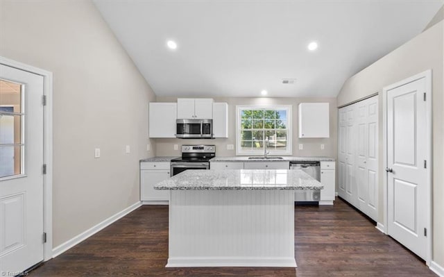 kitchen with stainless steel appliances, sink, a kitchen island, and white cabinets