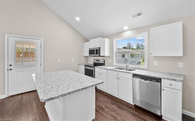 kitchen with sink, appliances with stainless steel finishes, white cabinetry, a center island, and light stone counters