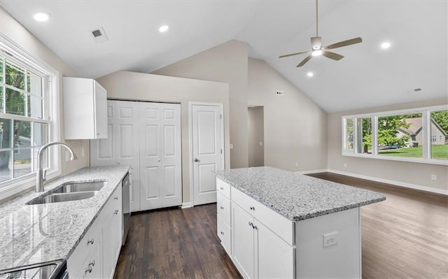 kitchen featuring light stone countertops, a kitchen island, sink, and white cabinets