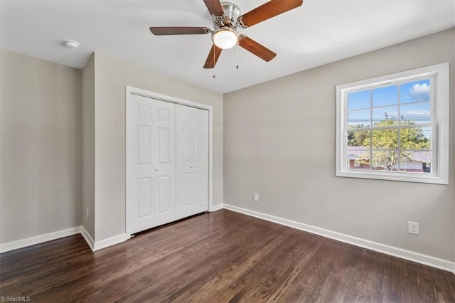 unfurnished bedroom with ceiling fan, dark hardwood / wood-style flooring, and a closet