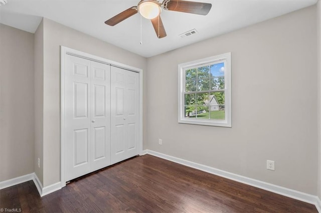 unfurnished bedroom featuring dark wood-type flooring, ceiling fan, and a closet