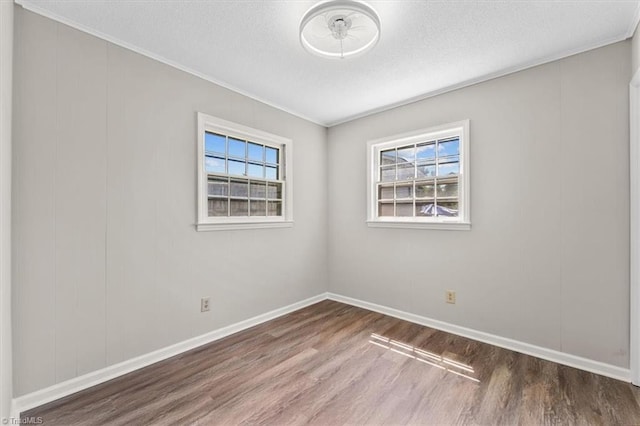 empty room with dark wood-type flooring, ornamental molding, a healthy amount of sunlight, and a textured ceiling