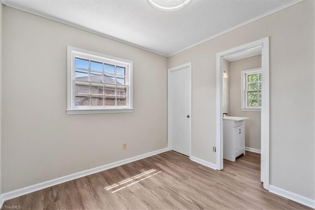 unfurnished bedroom with ornamental molding, a textured ceiling, and light wood-type flooring