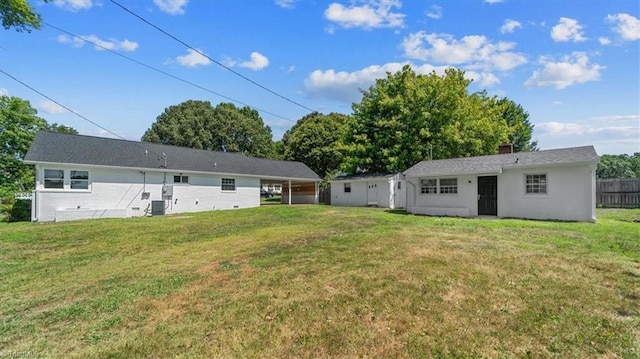 rear view of property with central AC and a lawn